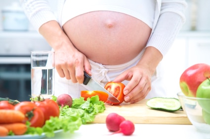 kobieta w ciąży krojąca warzywa